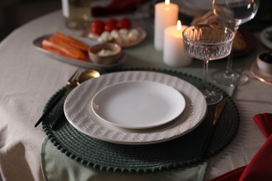 Table setting with burning candles, appetizers and dishware, closeup. Christmas celebration