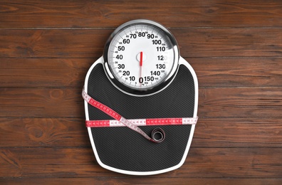 Scales and measuring tape on wooden background, top view. Weight loss