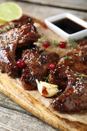 Photo of Tasty chicken wings glazed in soy sauce with garnish on wooden table, closeup