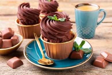 Photo of Delicious cupcakes with mint and chocolate pieces on wooden table, closeup
