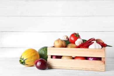 Wooden crate full of fresh vegetables on table. Space for text