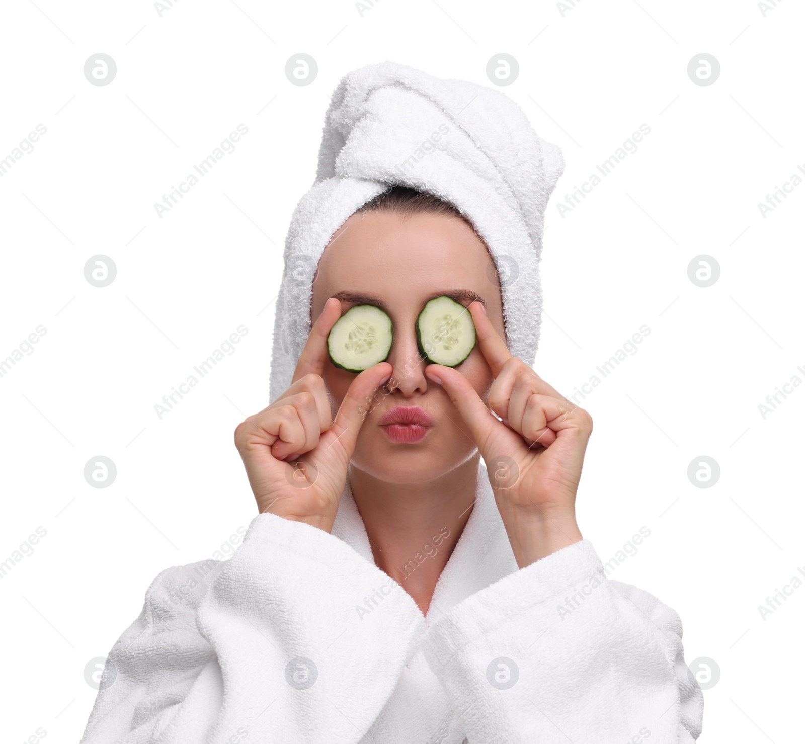 Photo of Beautiful woman in bathrobe covering eyes with pieces of cucumber and blowing kiss on white background