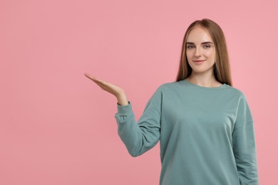Photo of Special promotion. Young woman showing something on pink background, space for text