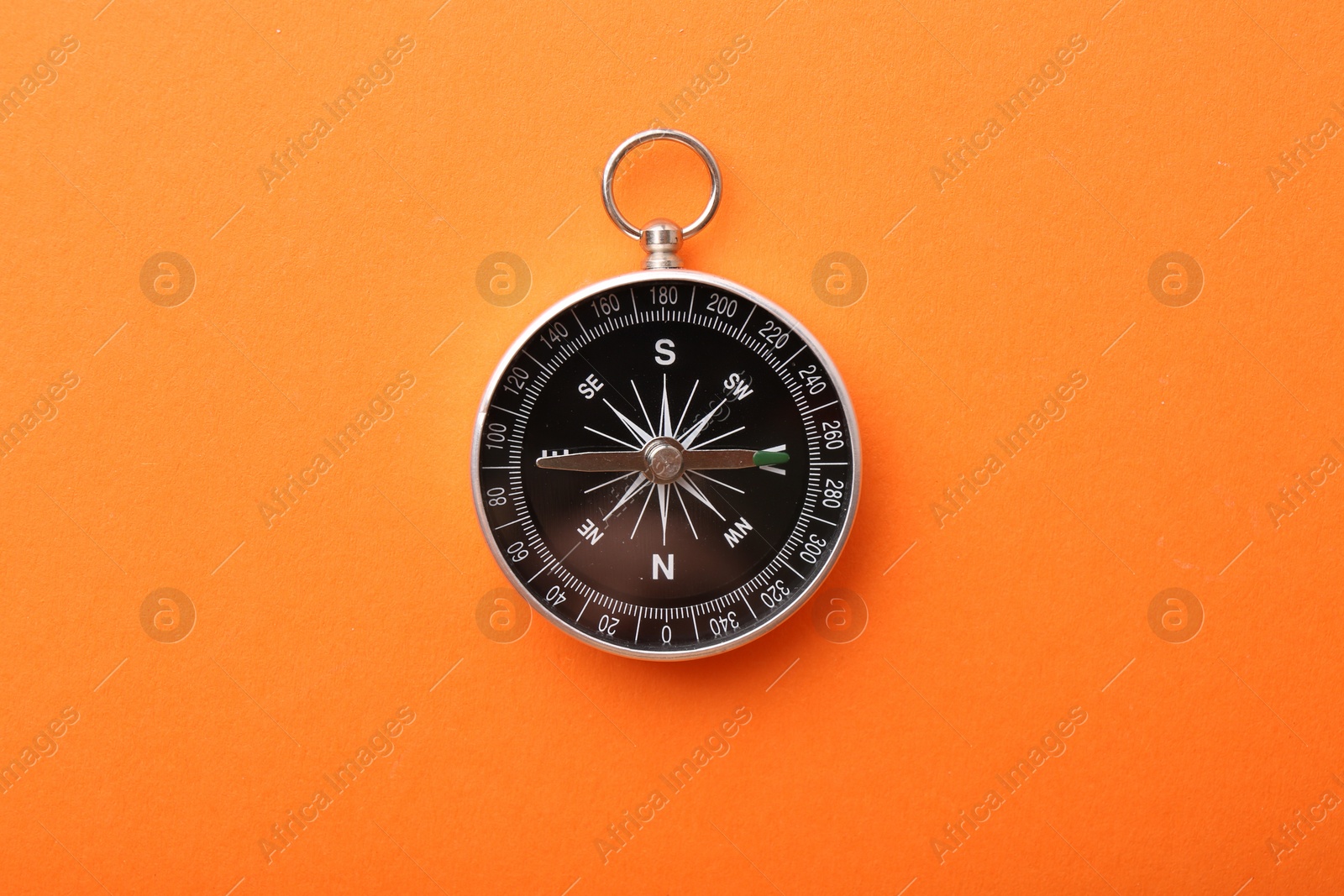 Photo of One compass on orange background, top view. Tourist equipment