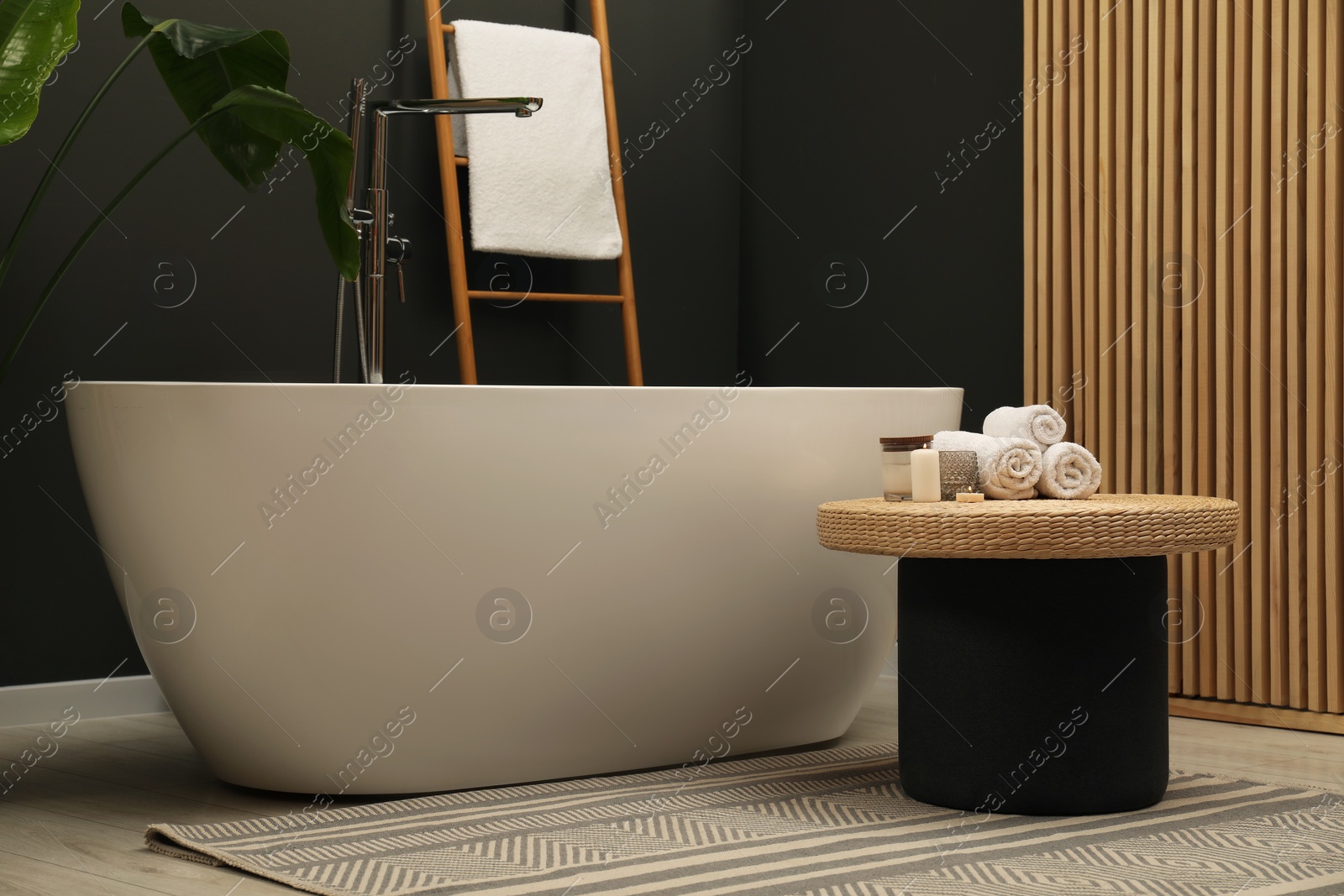 Photo of Spa day. Ceramic tub and wicker table in bathroom