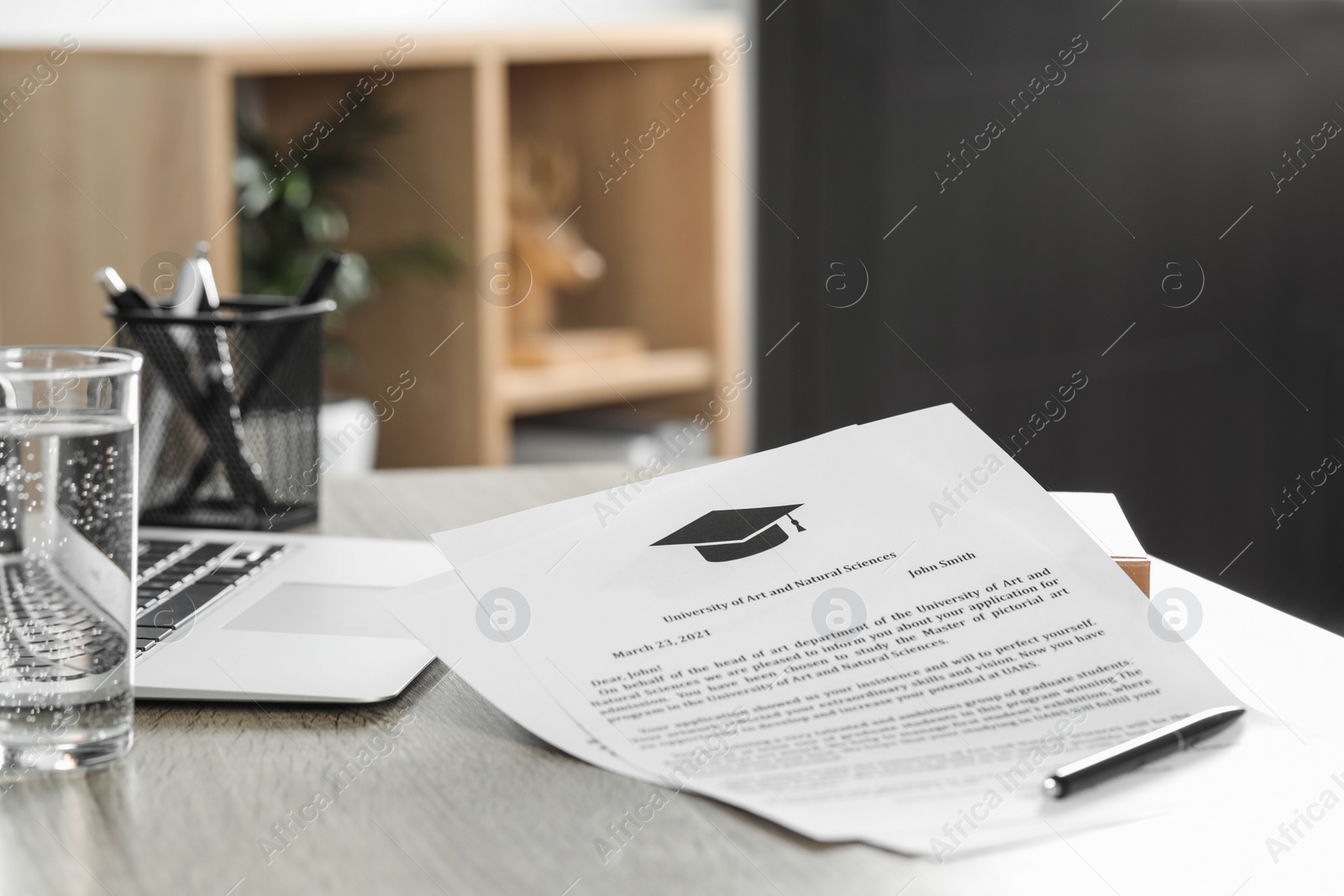 Photo of Acceptance letters from universities and laptop on wooden table indoors, closeup