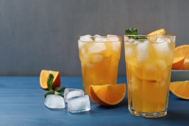 Photo of Delicious orange soda water on blue wooden table. Space for text