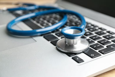 Photo of Laptop and stethoscope on table, closeup. Concept of technical support