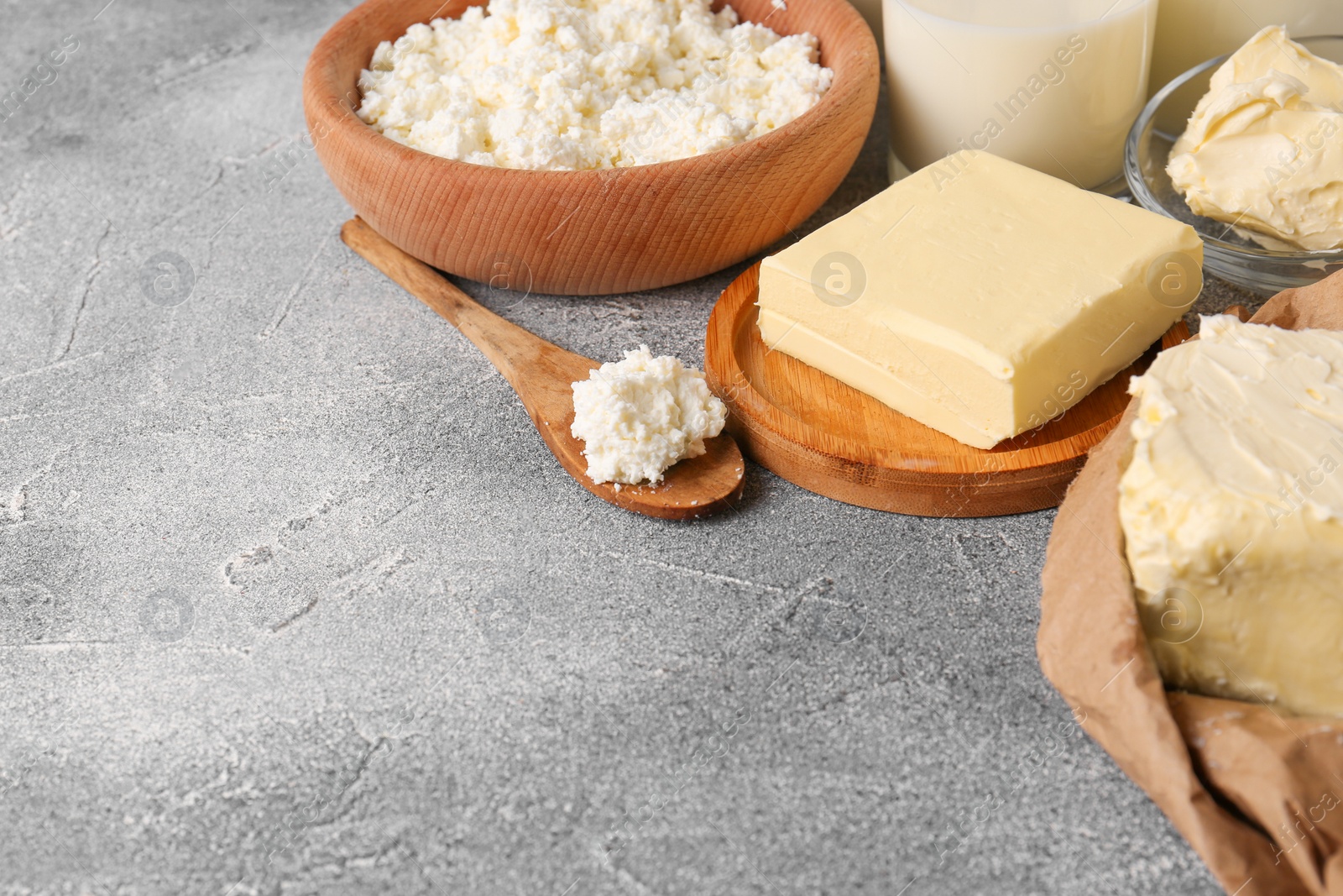 Photo of Tasty homemade butter and dairy products on grey table. Space for text