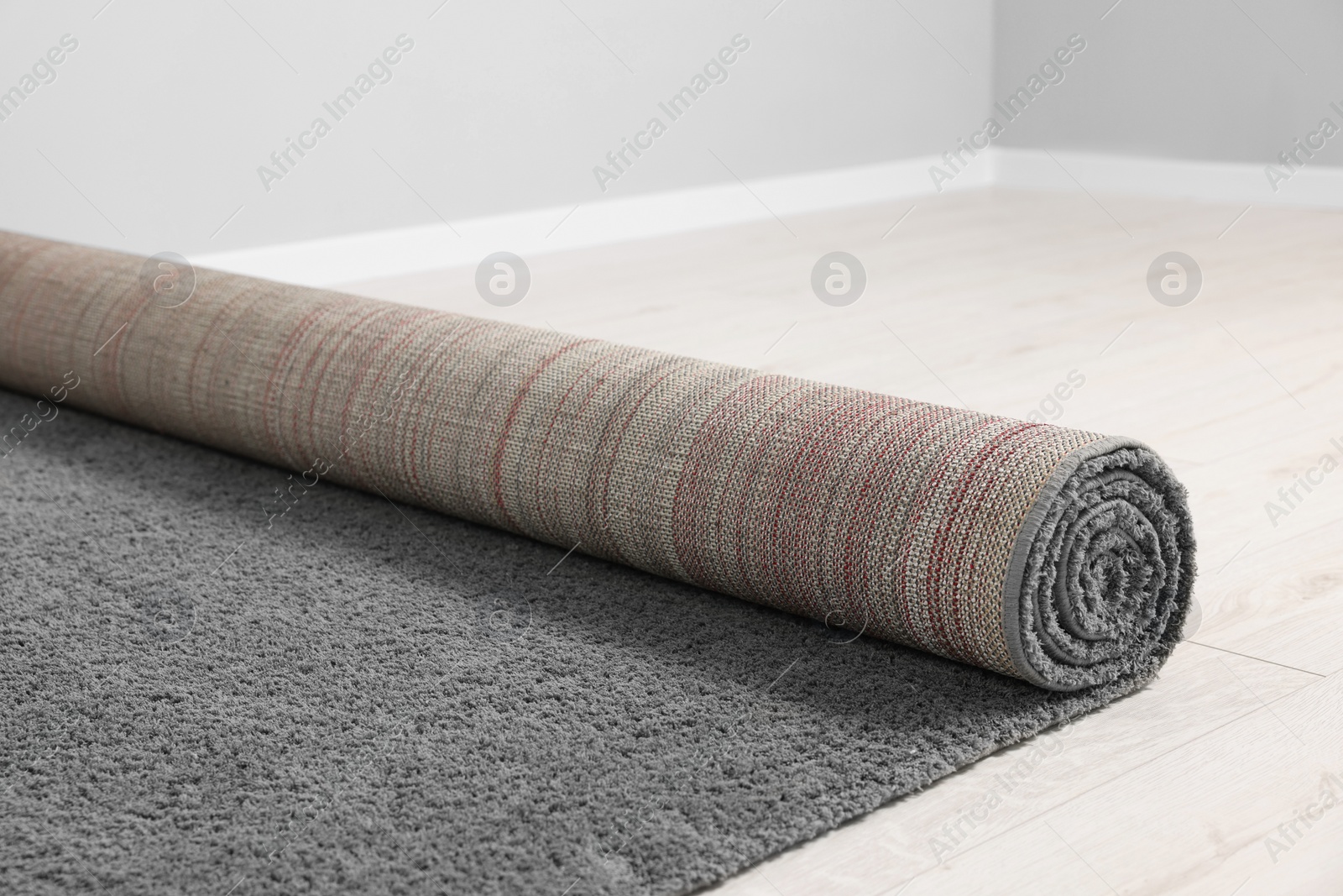 Photo of Rolled grey carpet on floor in room, closeup