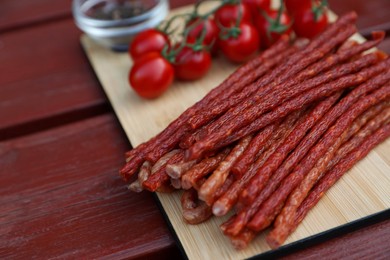 Photo of Tasty dry cured sausages (kabanosy) on wooden table, closeup. Space for text