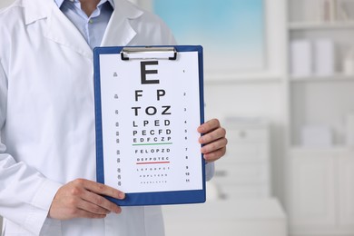 Ophthalmologist with vision test chart in clinic, closeup. Space for text