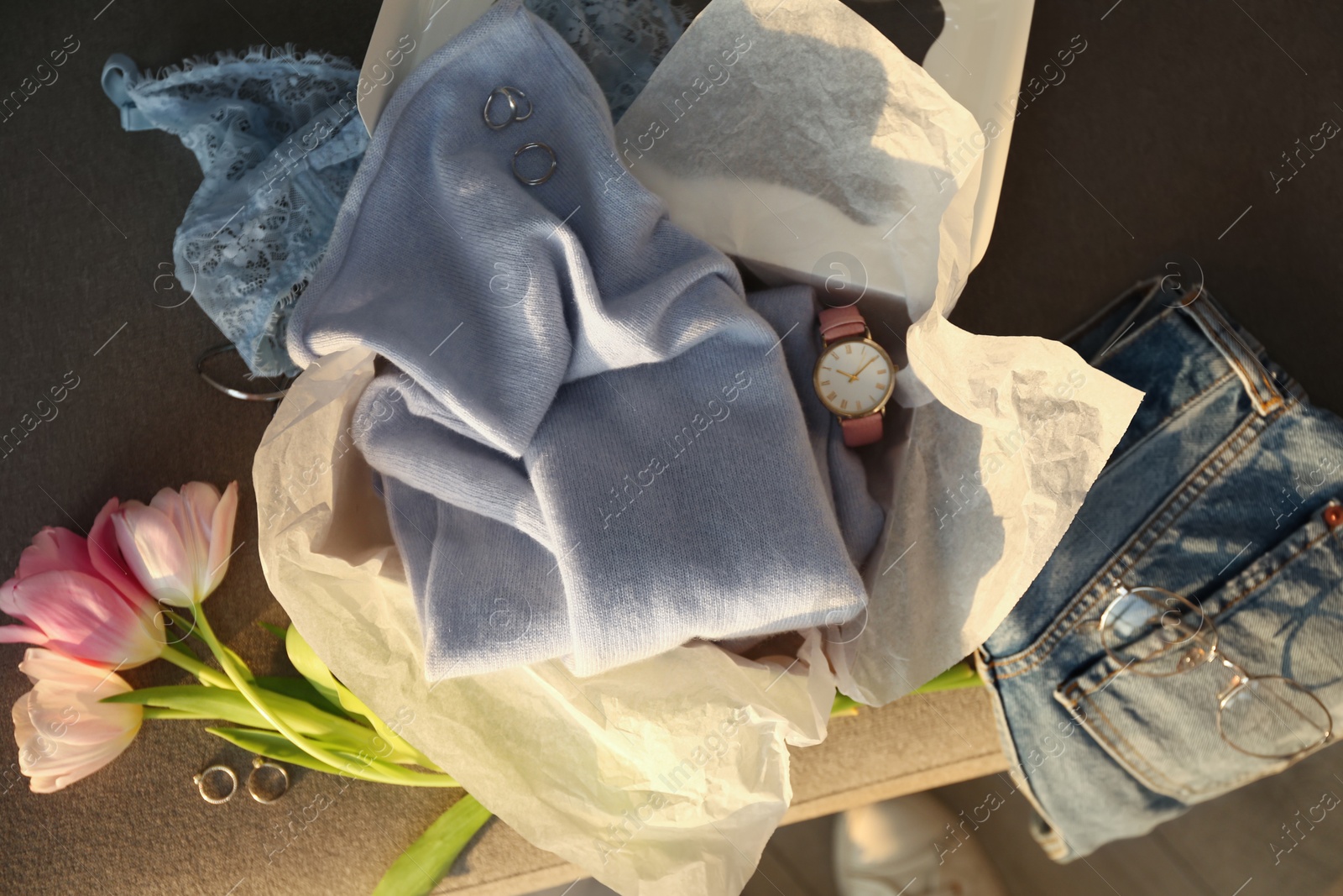 Photo of Soft cashmere sweater, jeans and tulips on sofa, flat lay