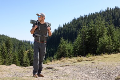 Man with backpack and sleeping mat in mountains. Space for text