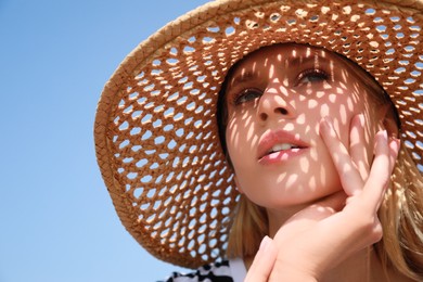 Beautiful woman with straw hat against blue sky on sunny day