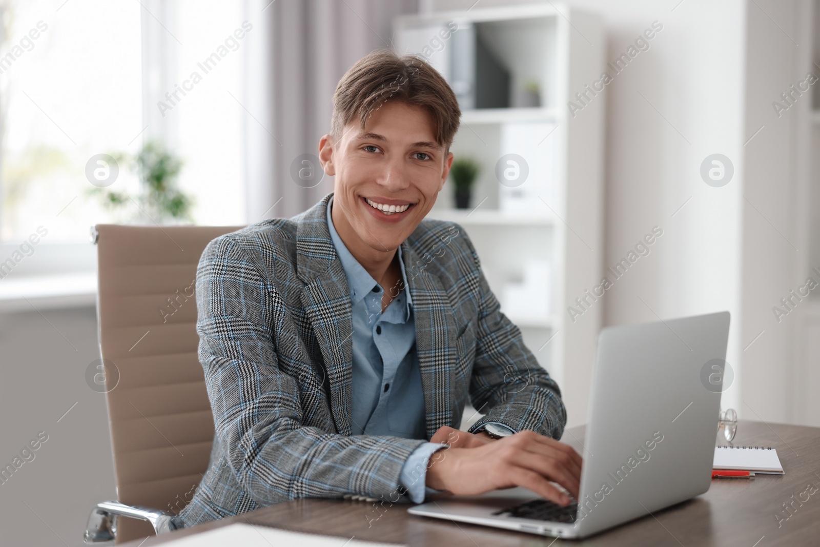 Photo of Man watching webinar at wooden table in office