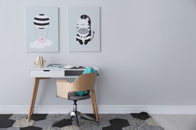 Photo of Child's room interior with desk and cute posters on light wall. Space for text