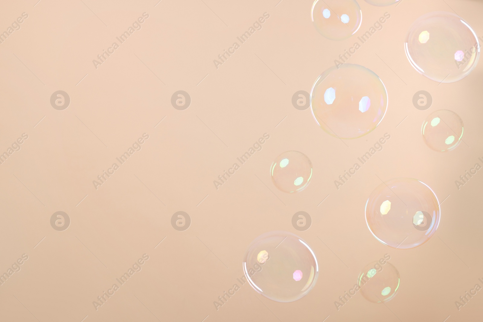 Photo of Many beautiful soap bubbles on beige background. Space for text