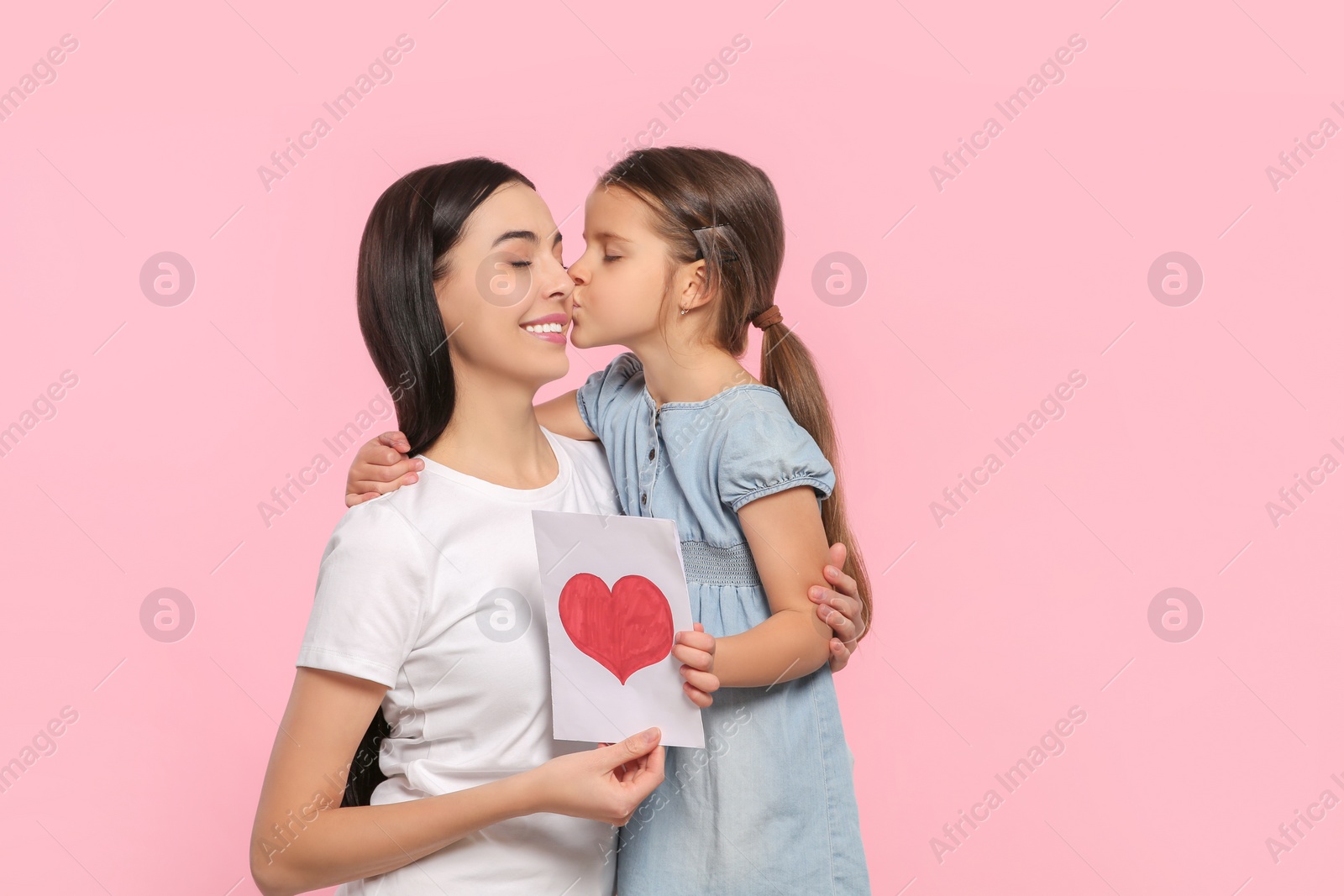 Photo of Happy woman with her cute daughter and handmade greeting card on pink background, space for text. Mother's day celebration