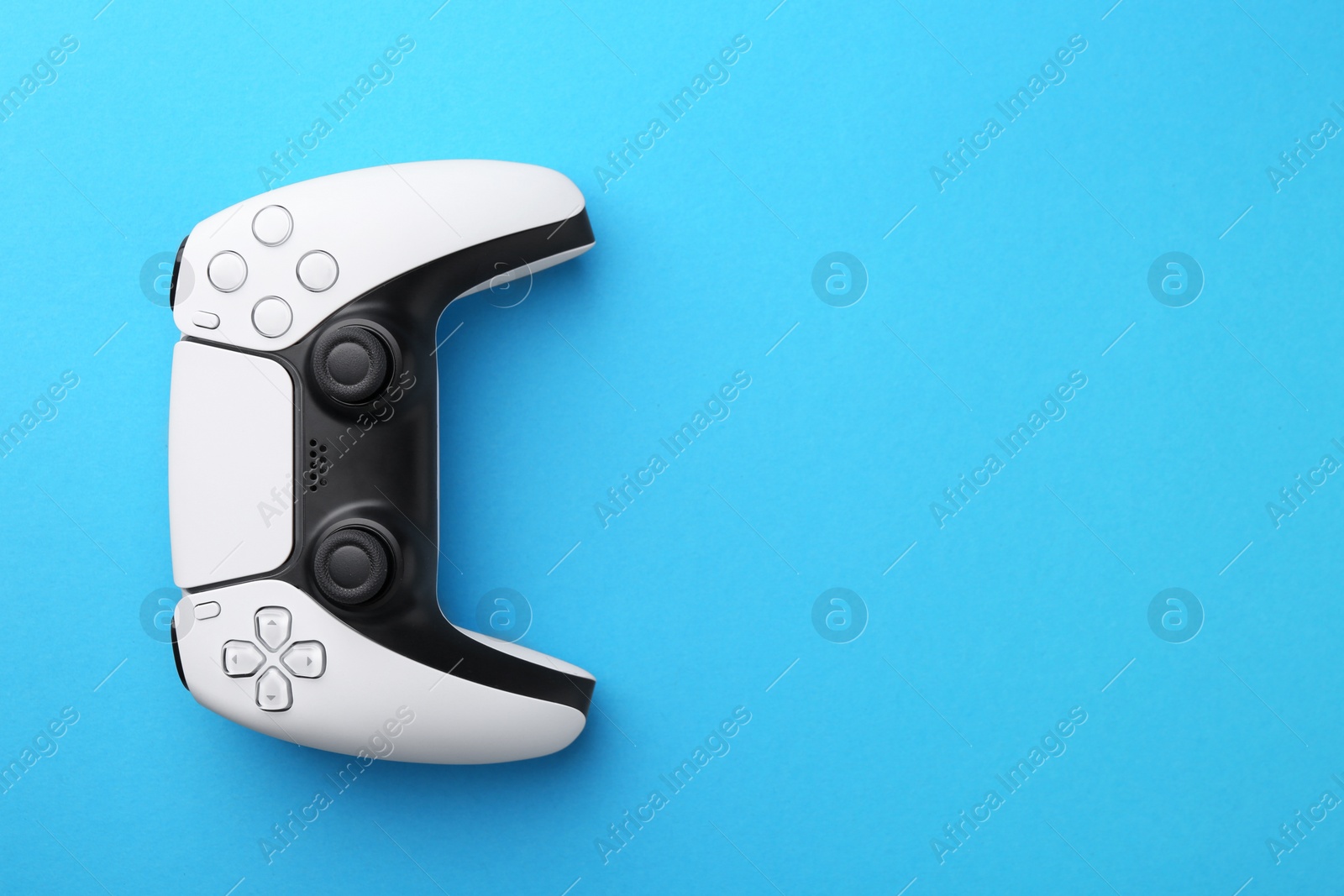 Photo of Wireless game controller on light blue background, top view. Space for text