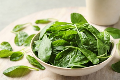 Bowl of fresh green healthy spinach on table