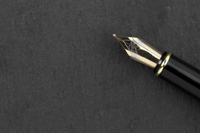 Stylish fountain pen on dark textured table, top view. Space for text