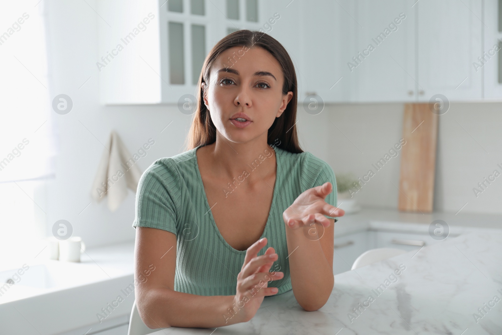 Photo of Young woman talking to his coworkers through video conference indoors, view from webcam