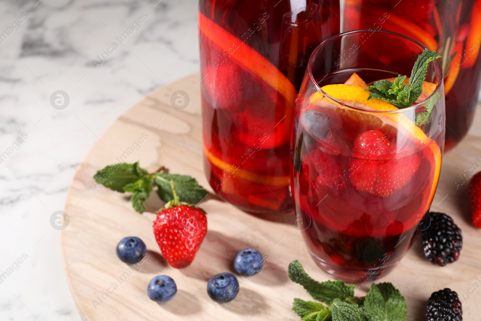 Photo of Delicious refreshing sangria and berries on white marble table, space for text