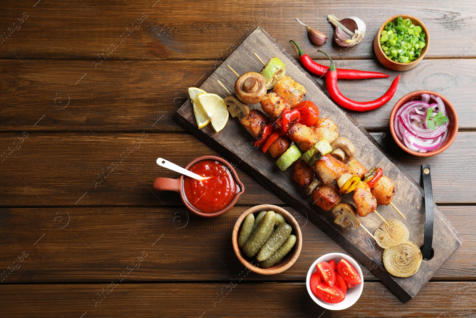 Photo of Delicious shish kebabs, mushroom, tomato and zucchini served on wooden table, flat lay. Space for text