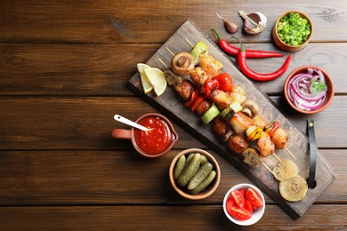Photo of Delicious shish kebabs, mushroom, tomato and zucchini served on wooden table, flat lay. Space for text