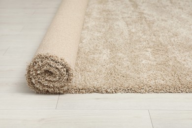 Photo of Rolled beige carpet on floor, closeup. Space for text