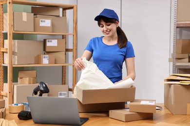 Photo of Post office worker packing parcel at wooden table indoors