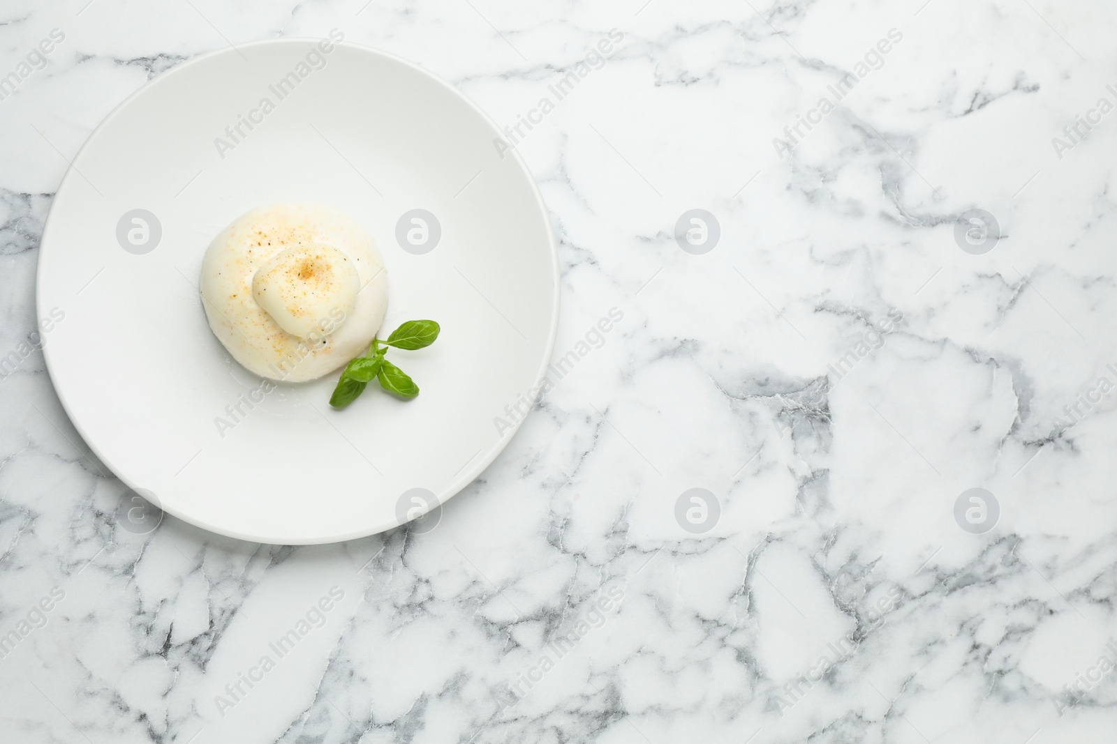 Photo of Delicious burrata cheese with basil on white marble table, top view. Space for text