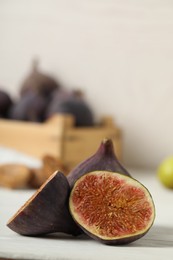 Tasty raw cut and whole figs on white table, closeup