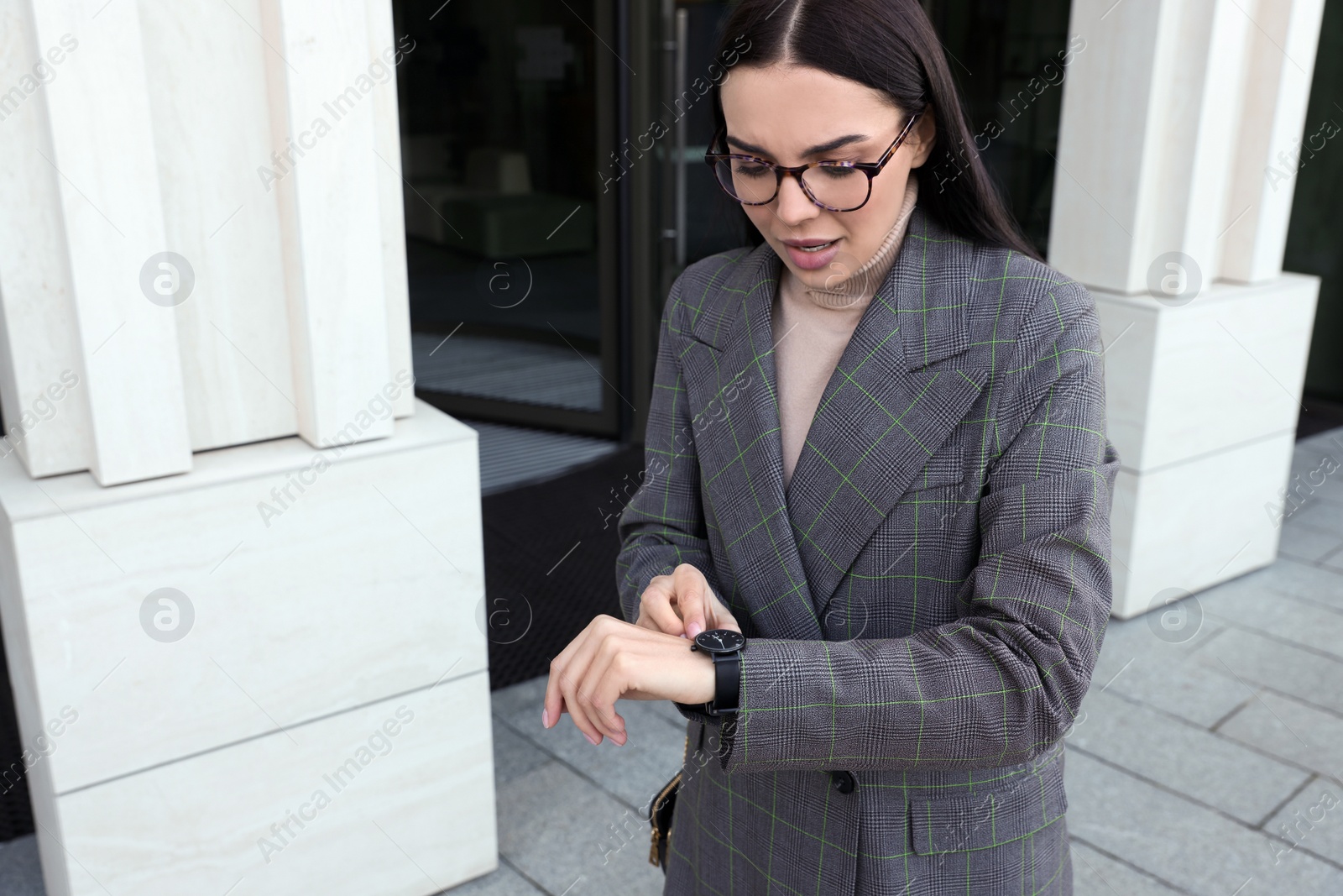 Photo of Emotional woman checking time on watch outdoors. Being late concept