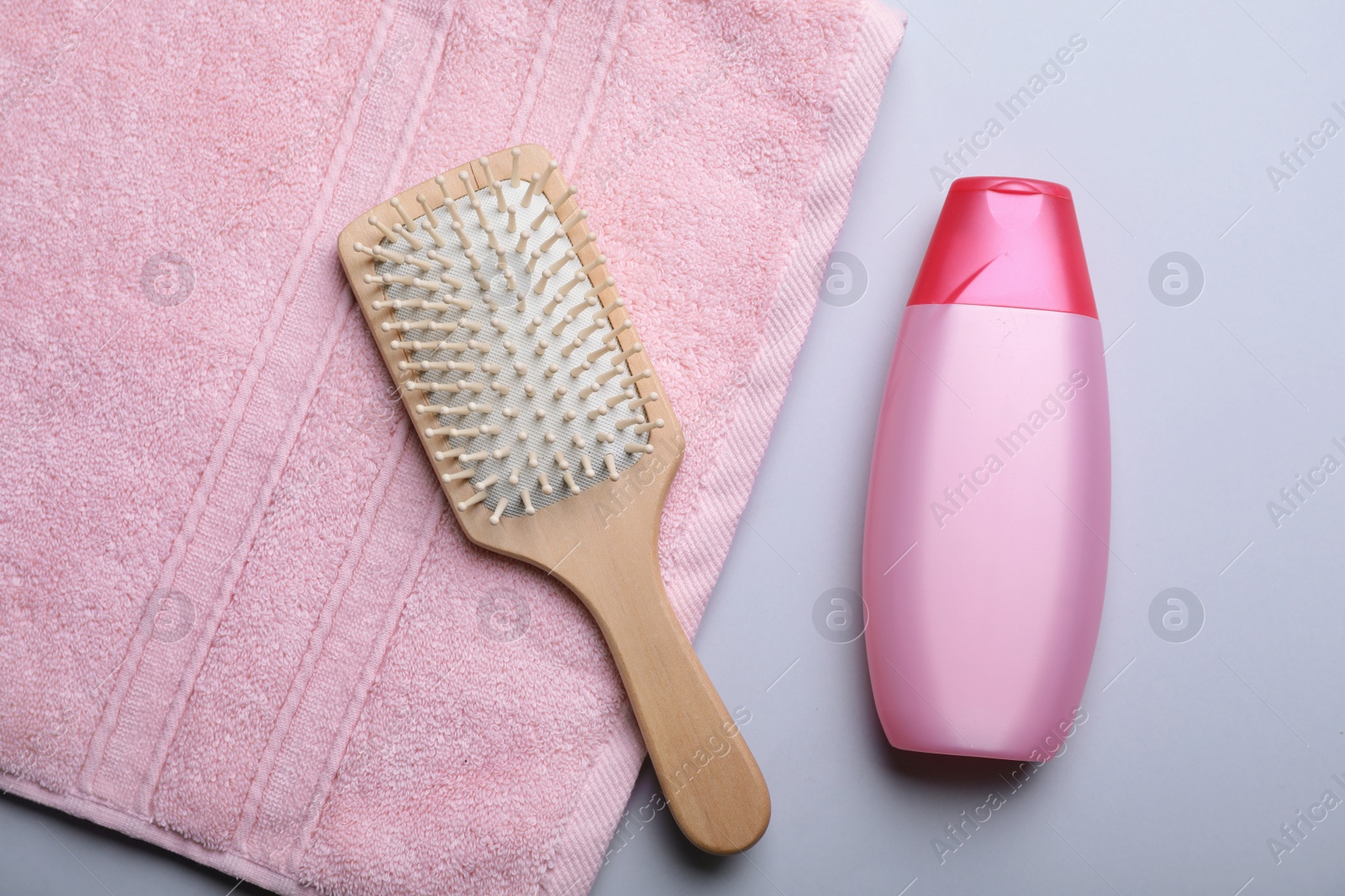 Photo of Bottle with shampoo, towel and brush on color background, flat lay