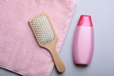 Bottle with shampoo, towel and brush on color background, flat lay