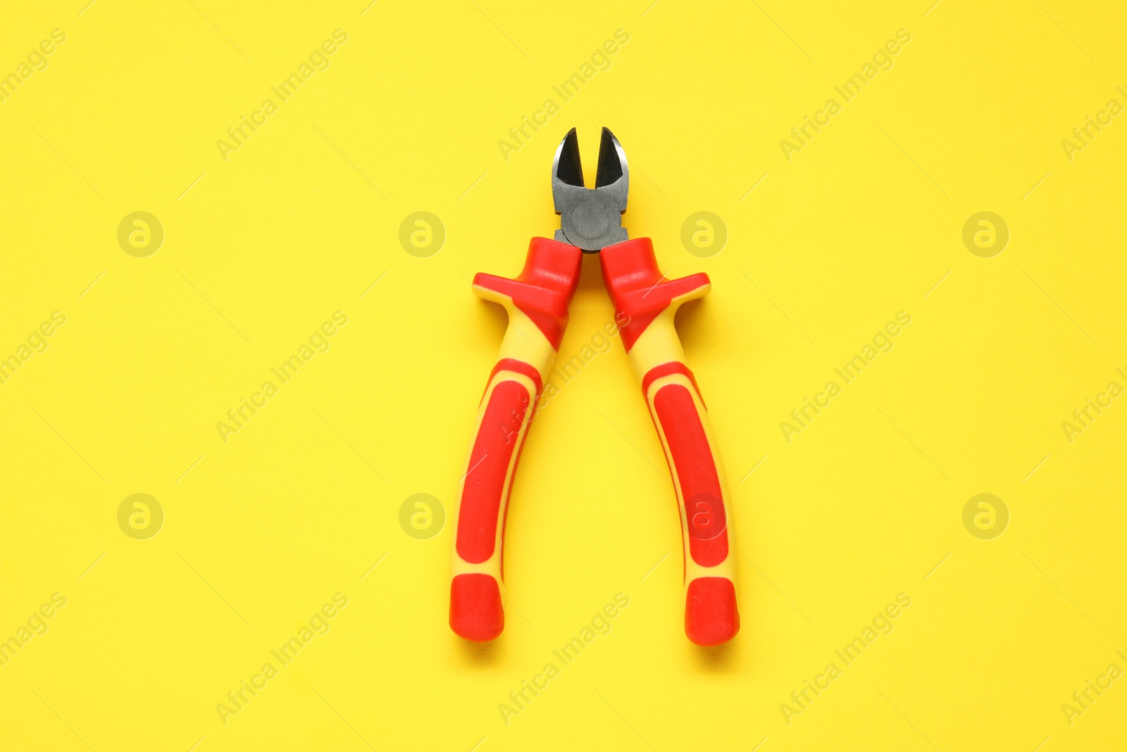 Photo of Diagonal pliers on yellow background, top view