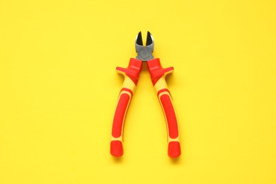 Photo of Diagonal pliers on yellow background, top view