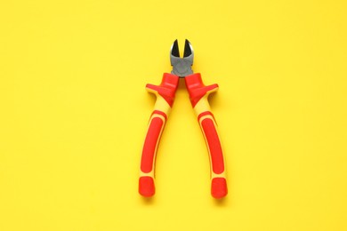 Diagonal pliers on yellow background, top view