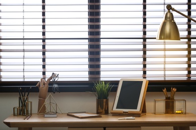 Stylish workplace with modern tablet on table at window. Ideas for interior design