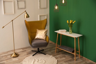 Photo of Modern interior with comfortable armchair and table near color wall