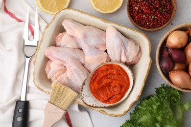 Photo of Flat lay composition with marinade, raw chicken and other products on light table