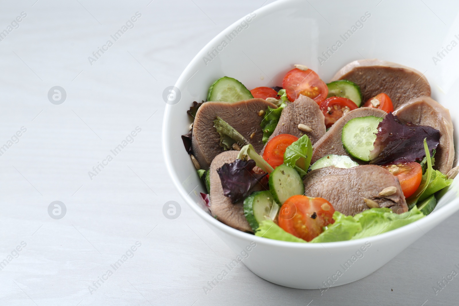 Photo of Delicious salad with beef tongue and vegetables on white wooden table, closeup. Space for text