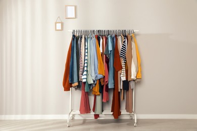Rack with stylish clothes near grey wall indoors. Fast fashion