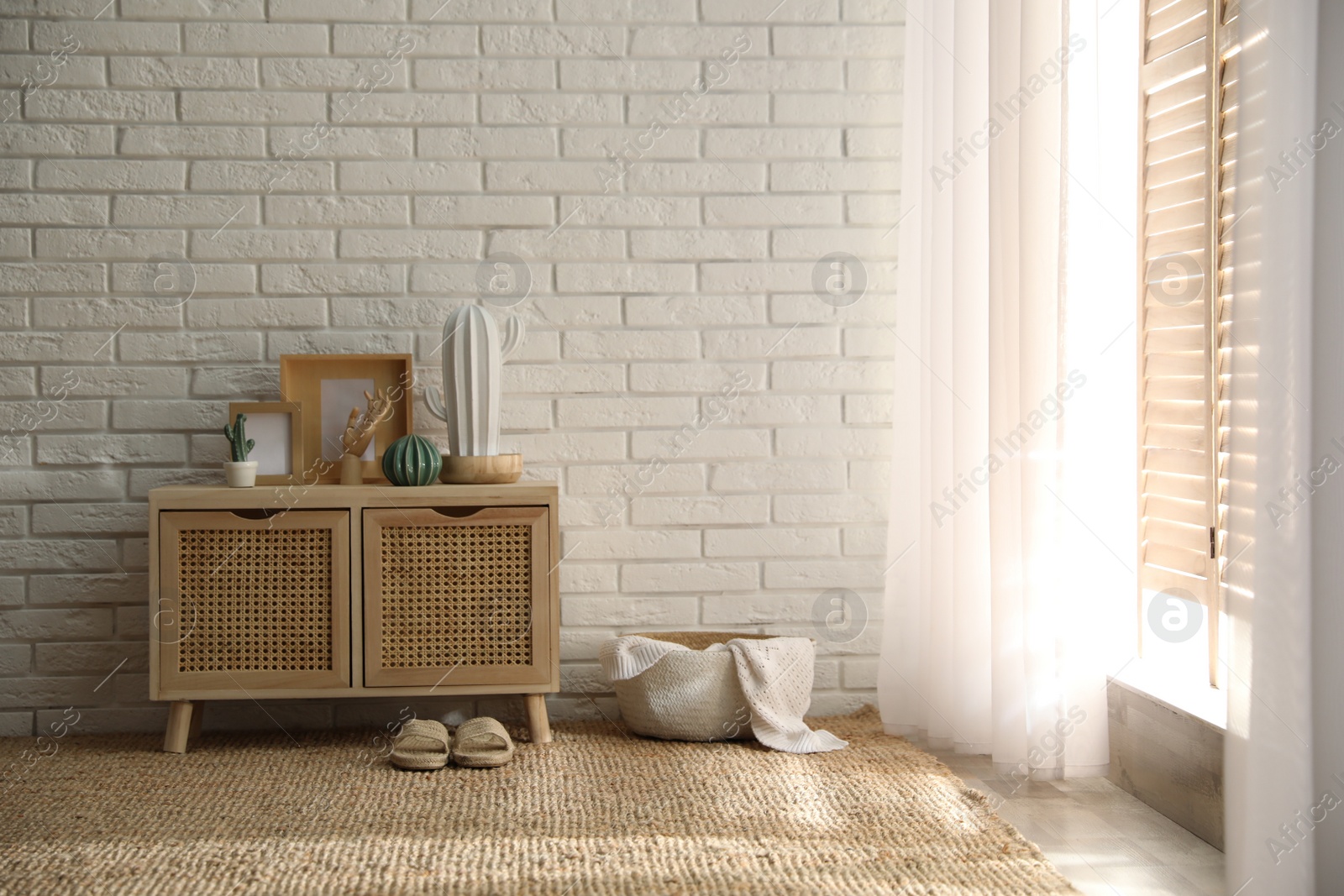 Photo of Stylish room interior with wooden cabinet near white brick wall