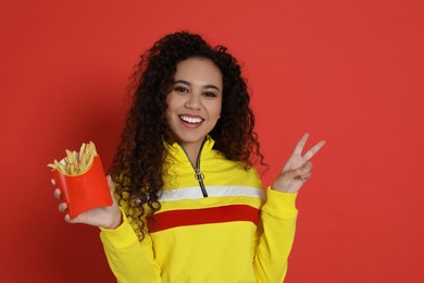 African American woman with French fries on red background