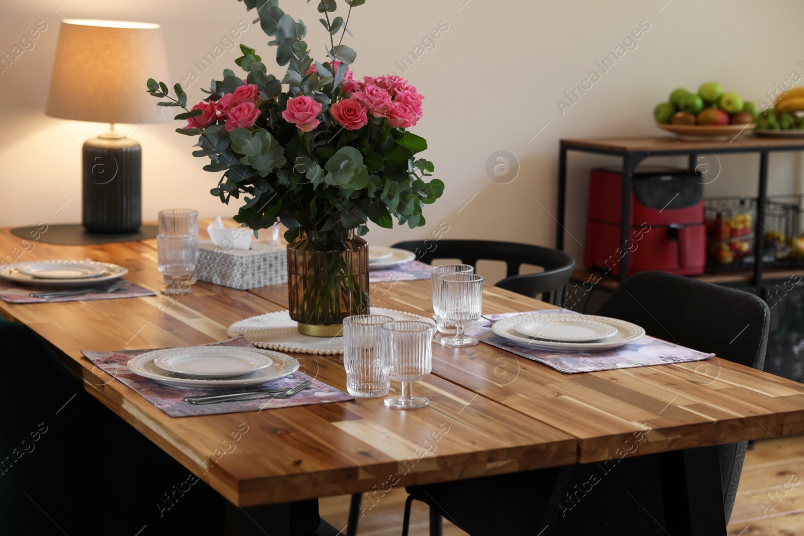 Photo of Beautiful table setting with bouquet indoors. Roses and eucalyptus branches in vase