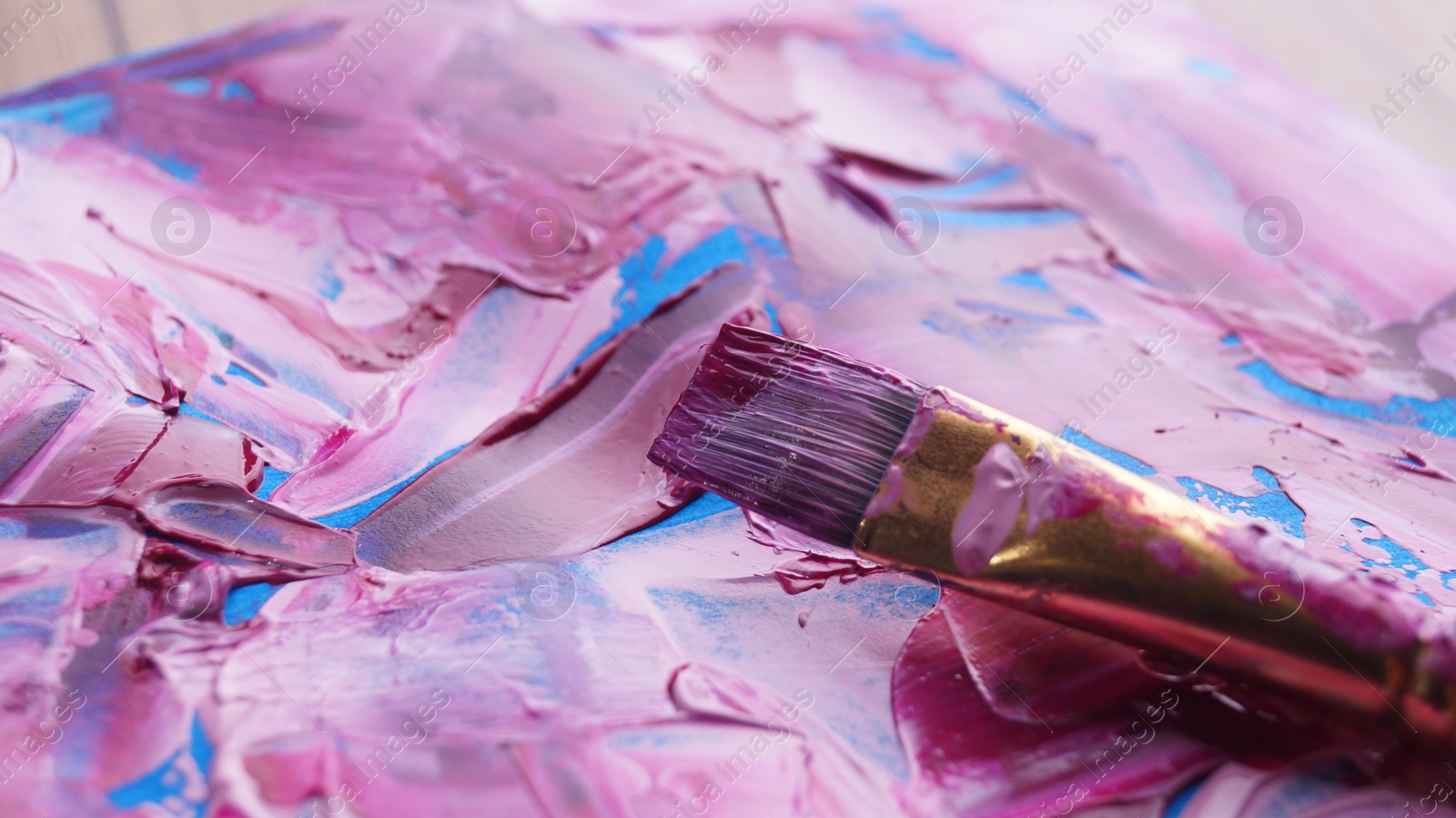 Photo of Brush on artist's palette with mixed paints, closeup