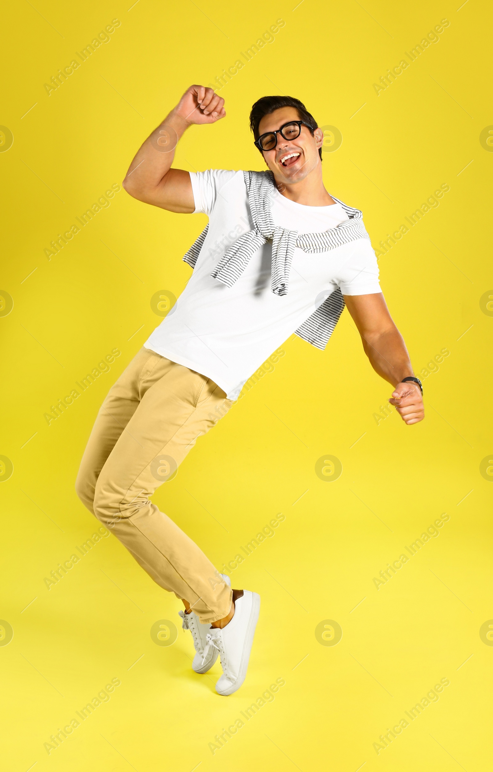 Photo of Handsome young man dancing on yellow background